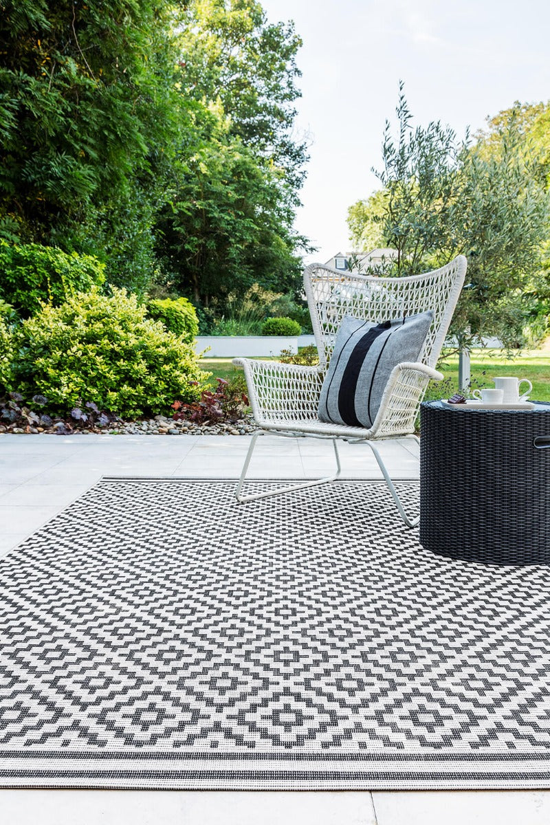 Woven grey and white rug with a modern geometric diamond pattern