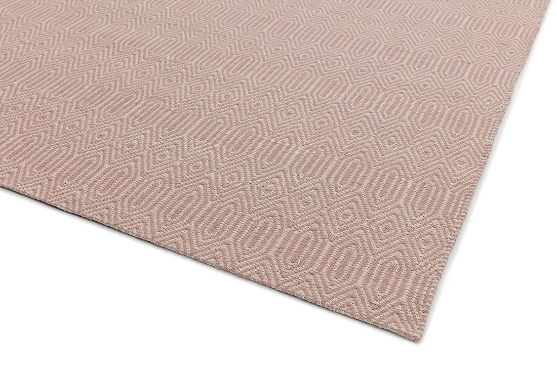 pink and white rug with a geometric aztec pattern