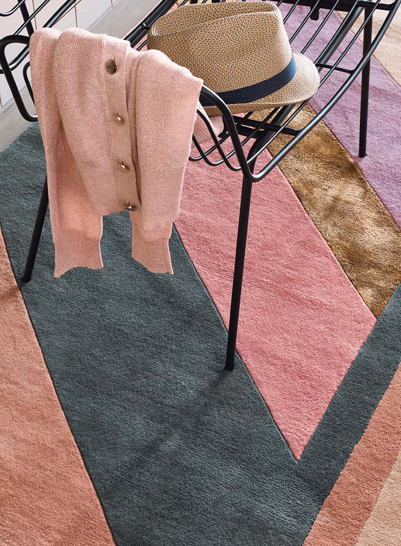 Striped pink, teal and gold rug in an abstract shape