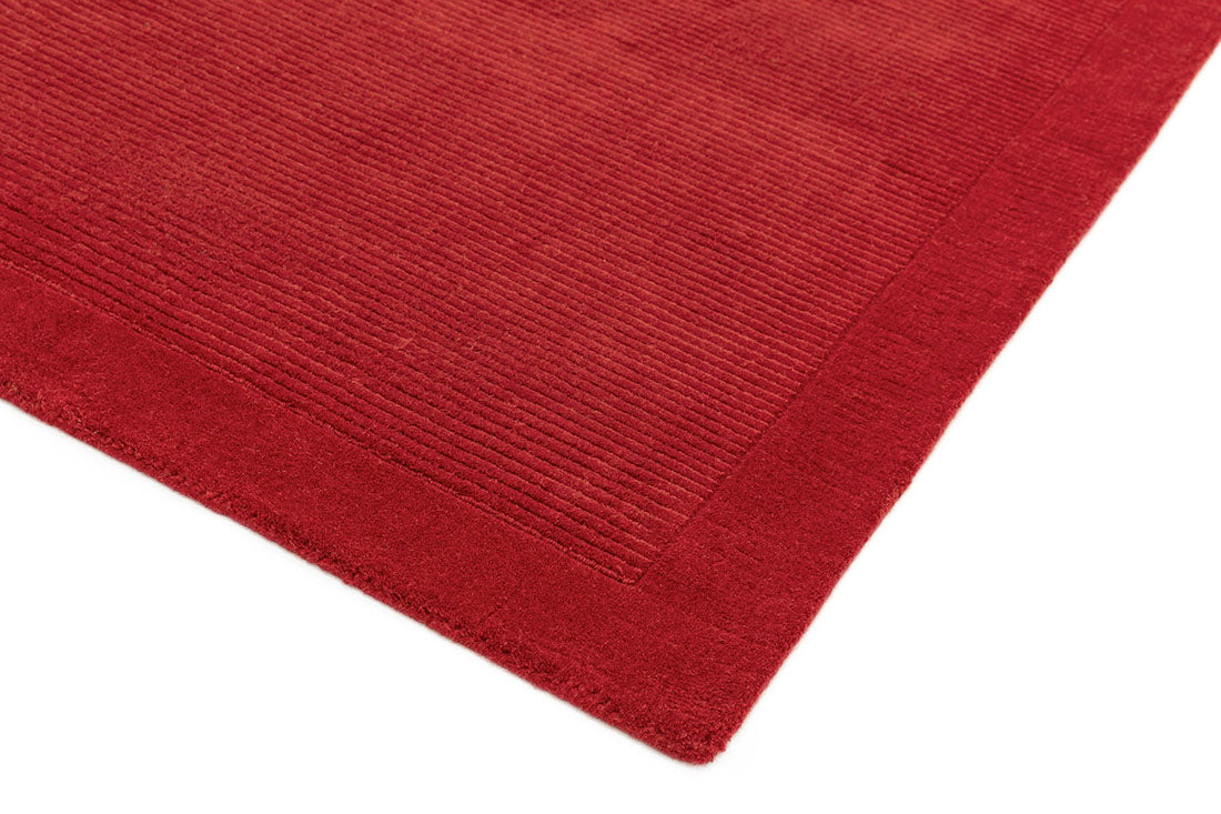 A plain red rectangle-shaped wool rug with thin border.