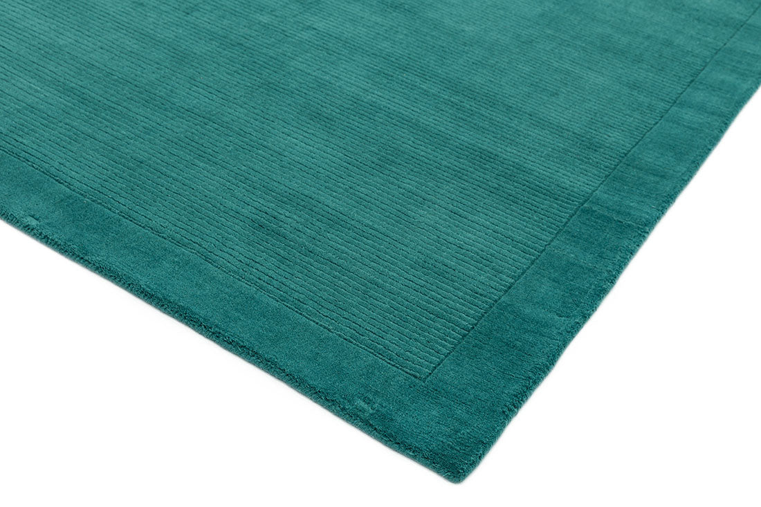A teal blue rectangle-shaped wool rug with thin border.