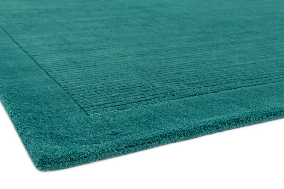 A teal blue rectangle-shaped wool rug with thin border.