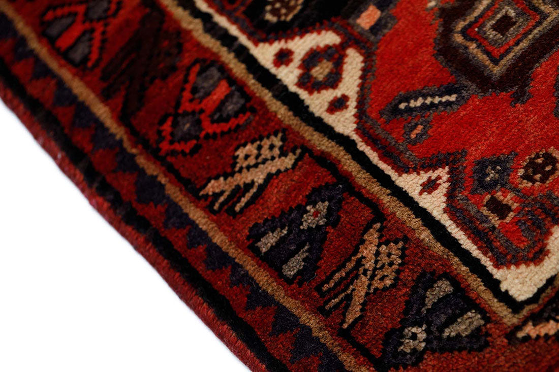 Handknotted Persian runner rug in red with touches of black and cream 
