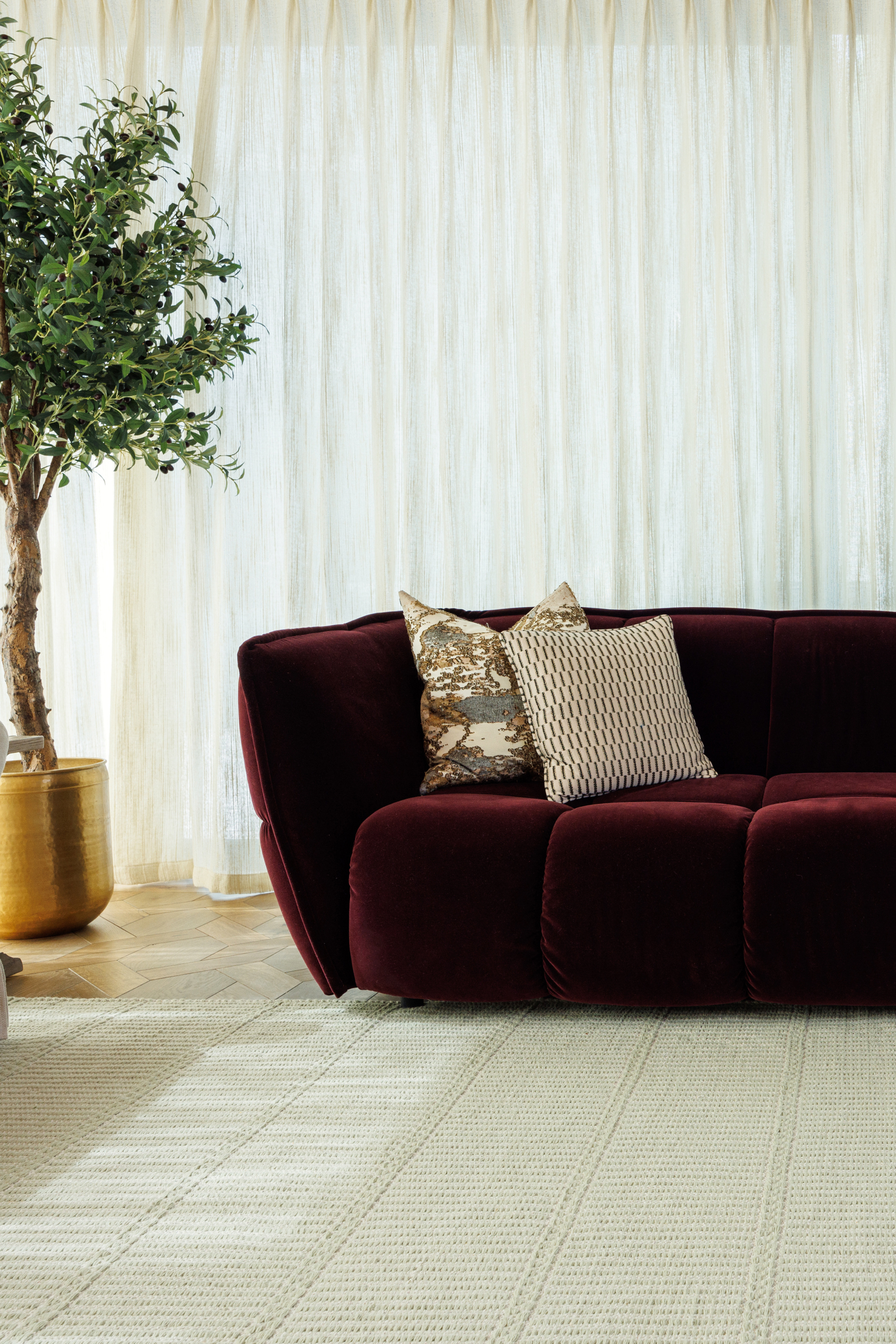wool and cotton rug in soft olive hues featuring a design inspired by ancient irish script palced under a couch in a living room 