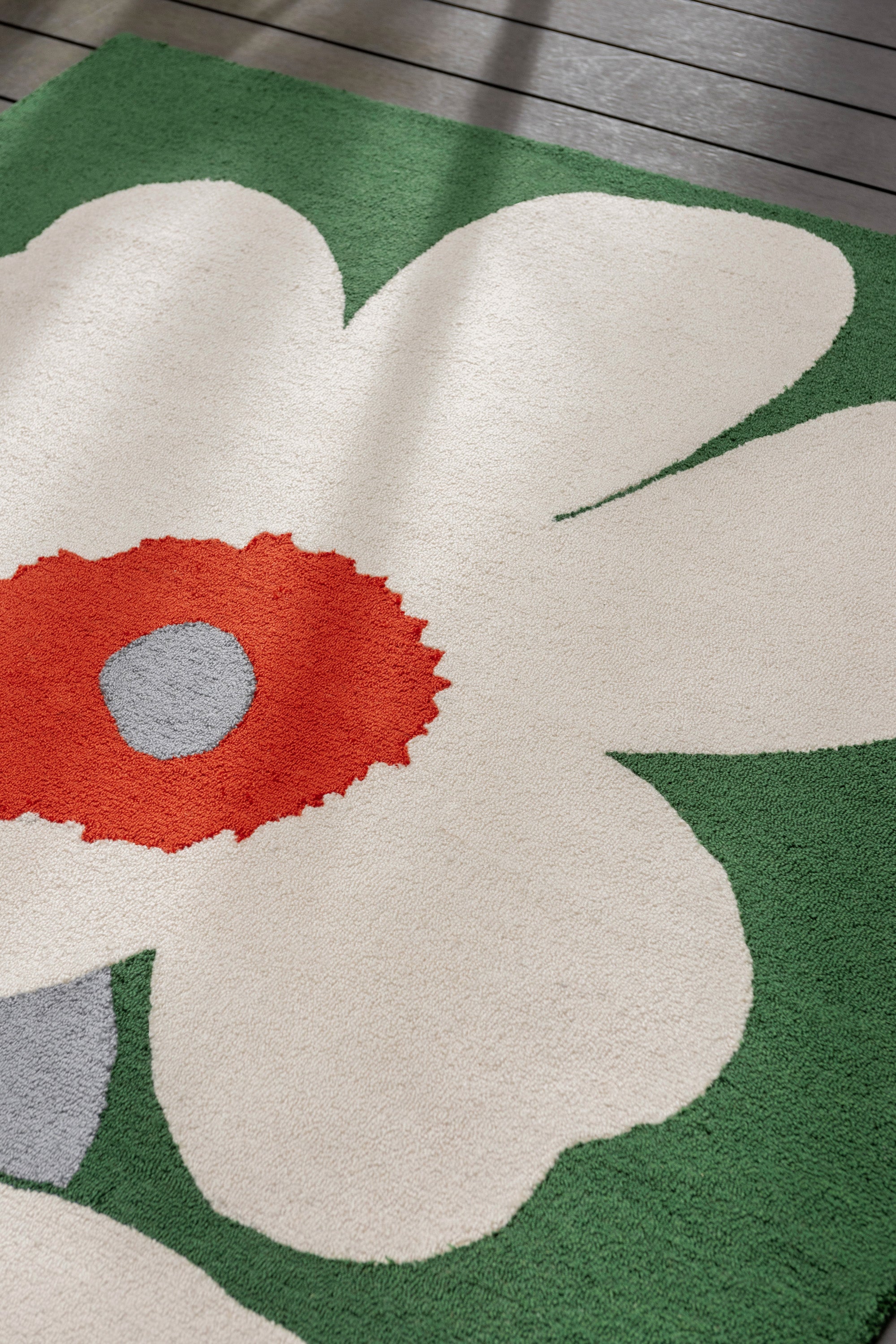 Green rug with white and orange floral motif