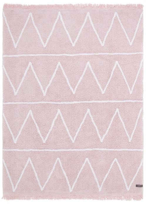 Rectangular pink rug decorated with white zig-zag design and fringed border