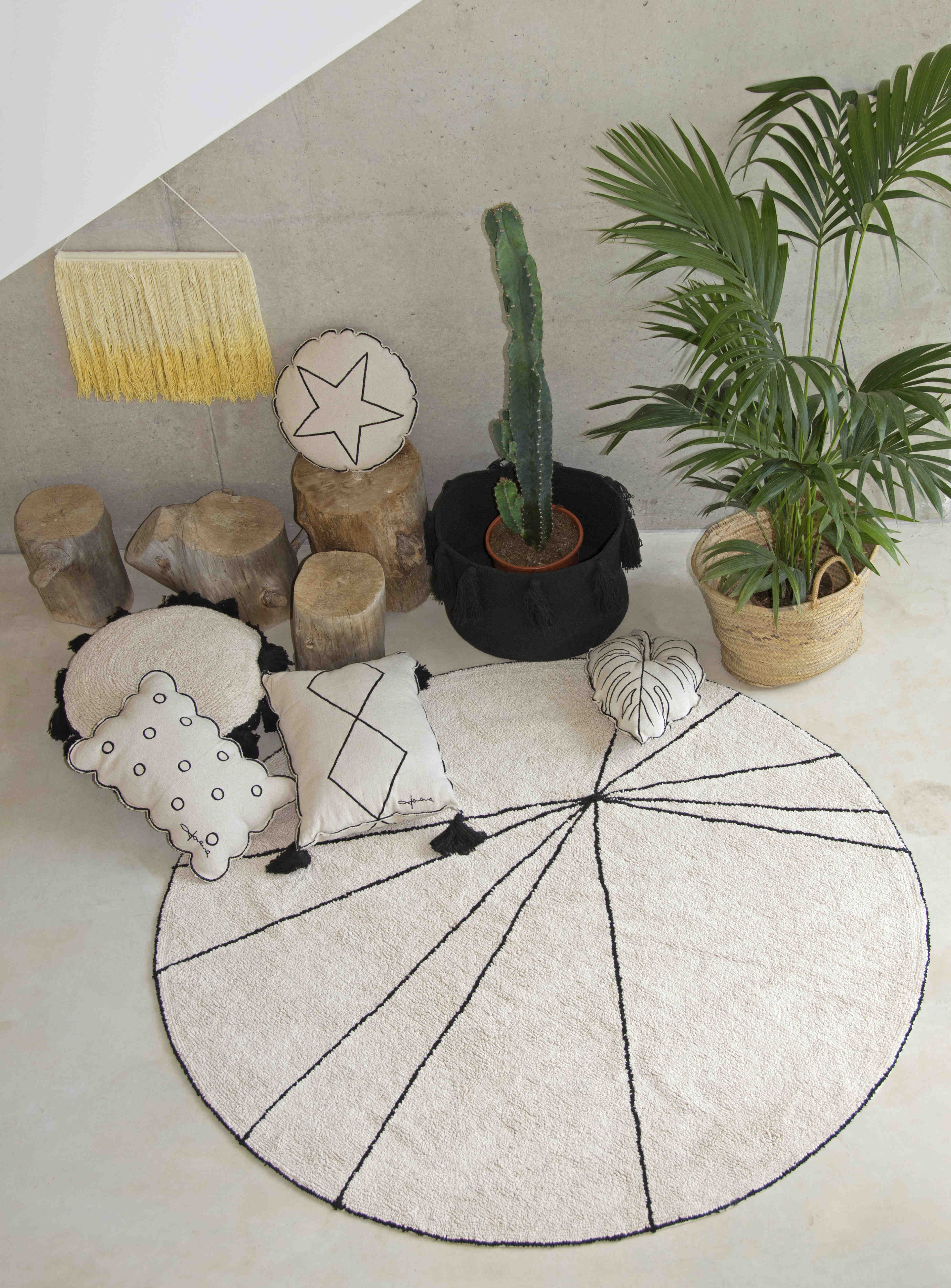 A circular shaped beige cotton rug decorated with geometric black lines