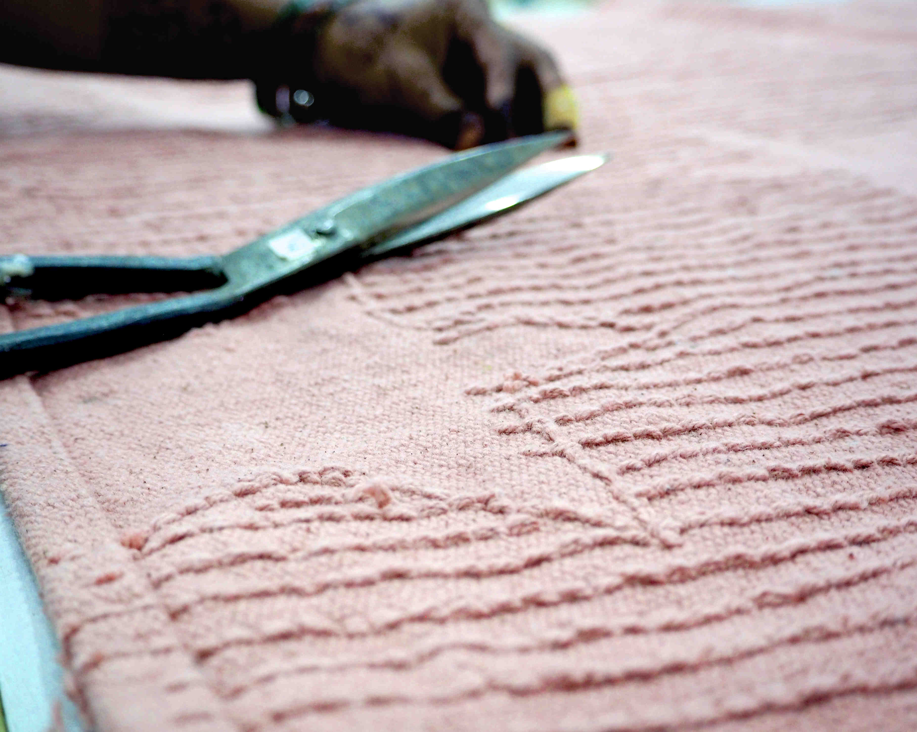 Rectangular pink cotton rug decorated with exposed stars and a tassel border.