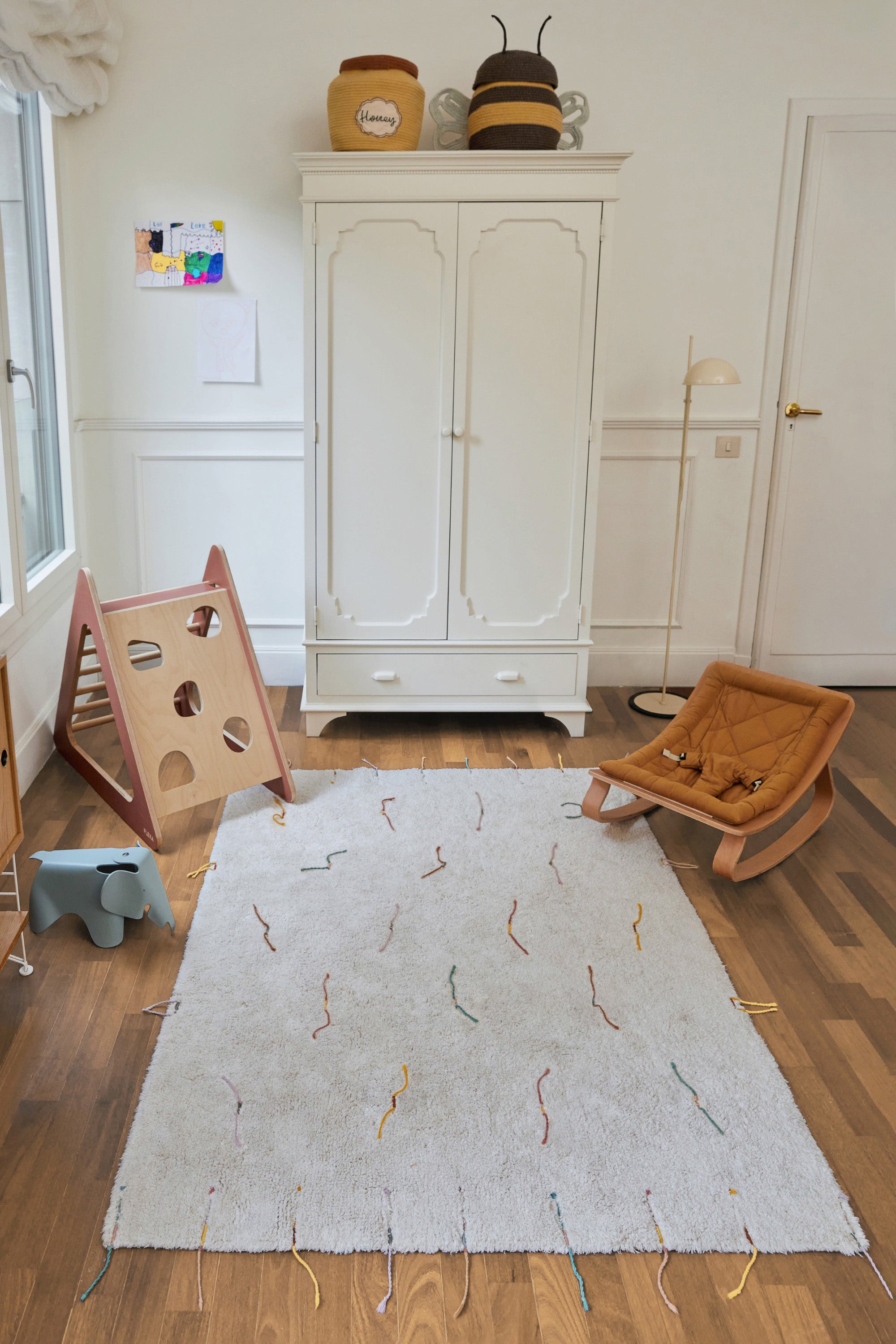 Plain cream rug with multicolour lined pattern and added wildflower toys