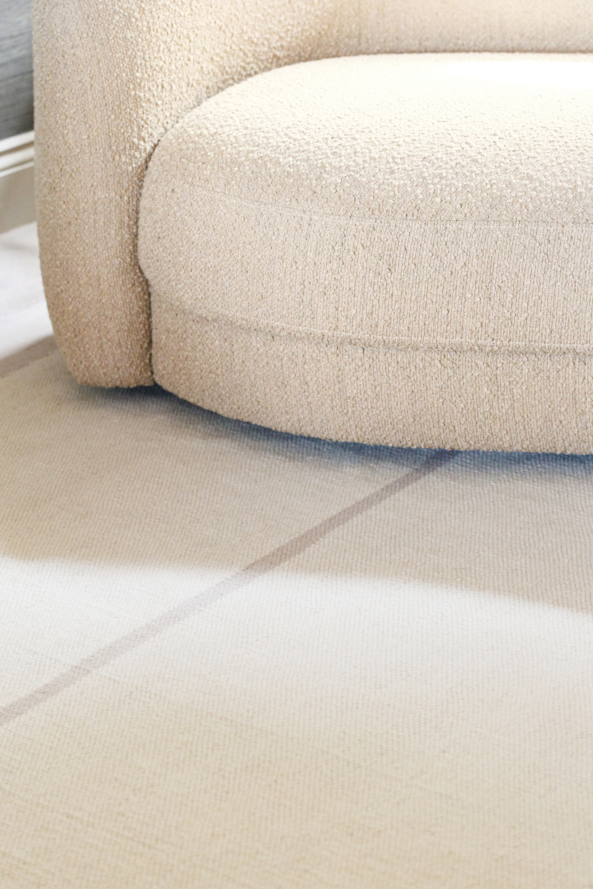Neutral greige wool and cotton rug featuring an ivory angular design placed under a couch 