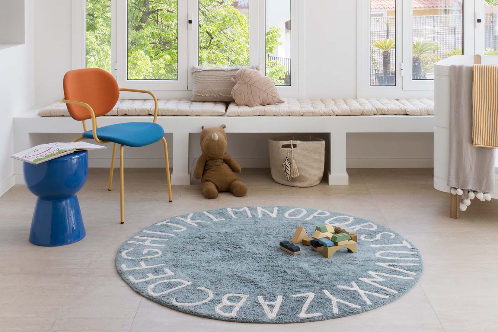 Circular blue cotton rug decorated with a natural beige alphabet border