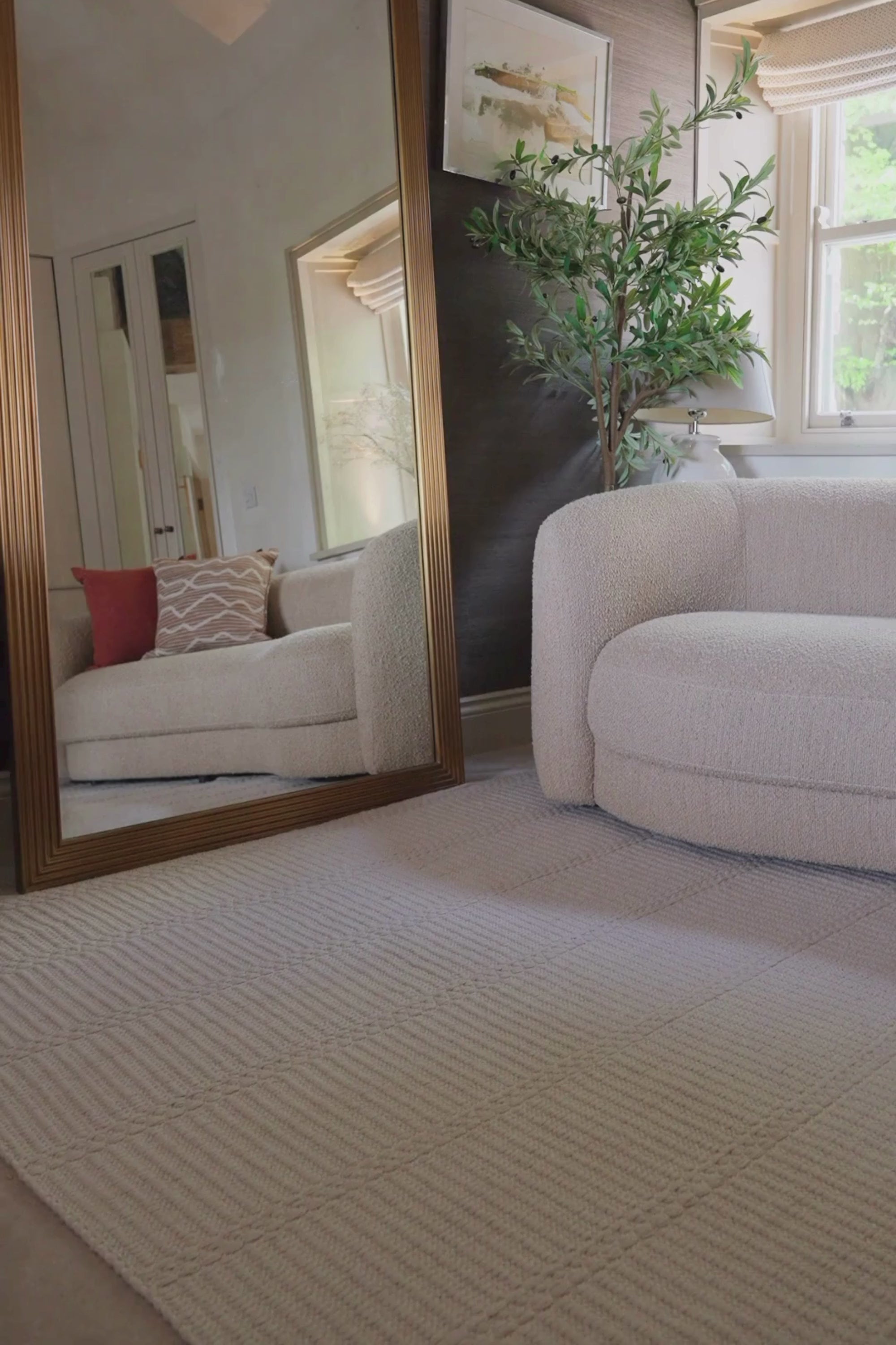 a video of a beige wool and cotton rug featuring a design inspired by ancient irish script placed under a couch in a living room