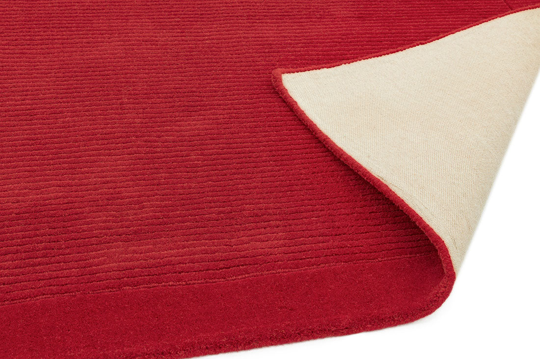 A plain red rectangle-shaped wool rug with thin border.