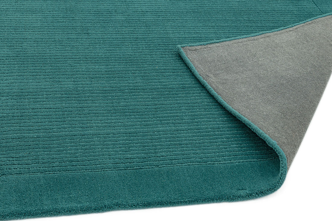 A teal blue rectangle-shaped wool rug with thin border.